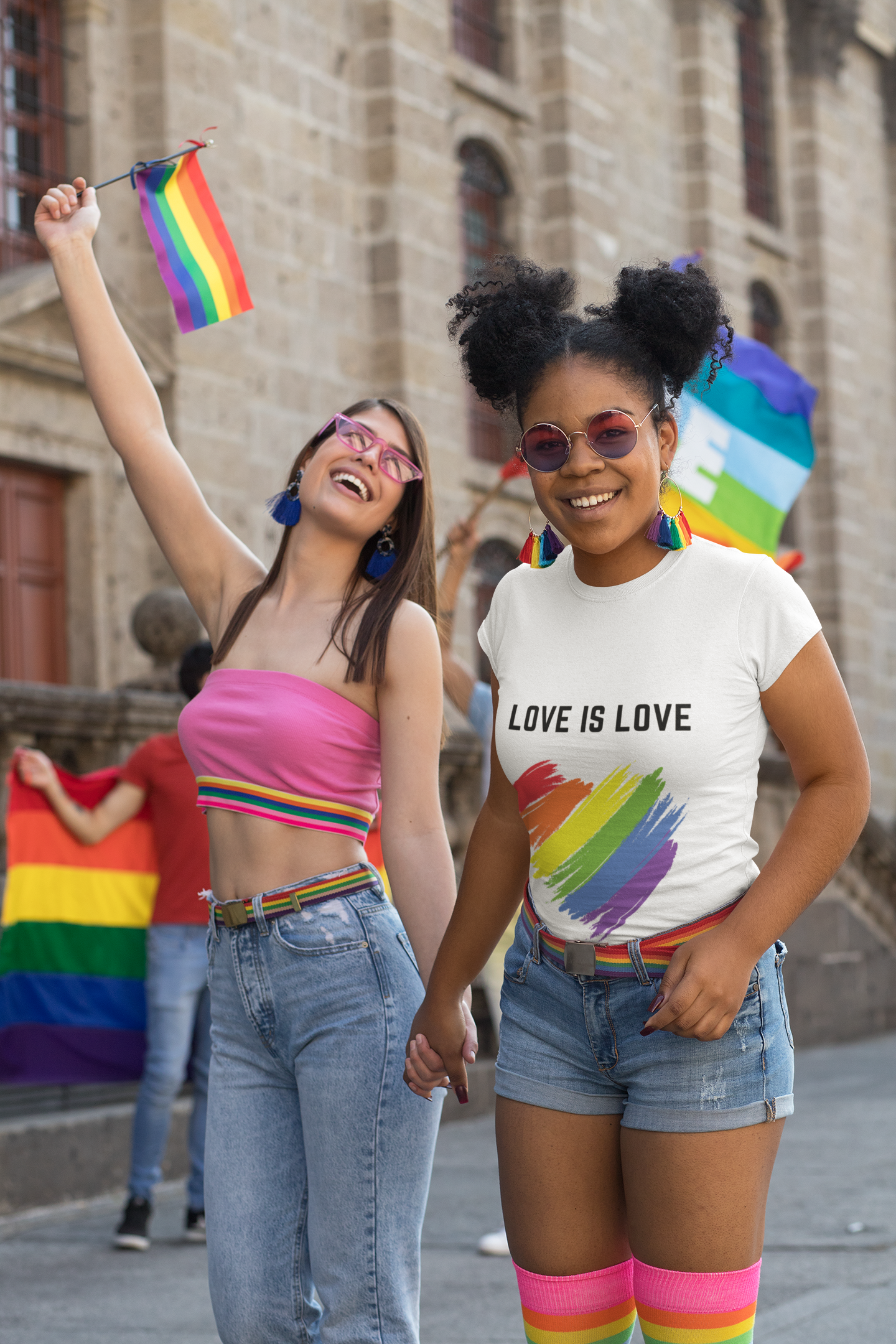 Pride Parade, one person wearing a pink top the other one wearing a white Love is Love T-Shirt.